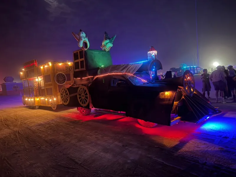 The locomotive-styled art car towing the blackjack wagon at night